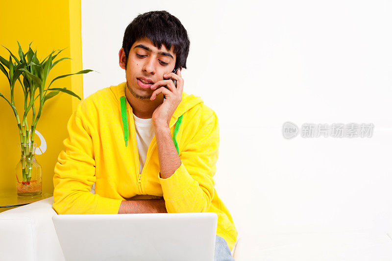 年轻的印度男孩用手提电脑打电话