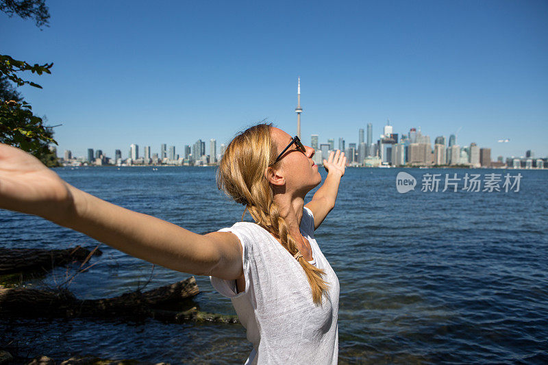 在加拿大多伦多市，一位快乐的年轻女子伸出双臂