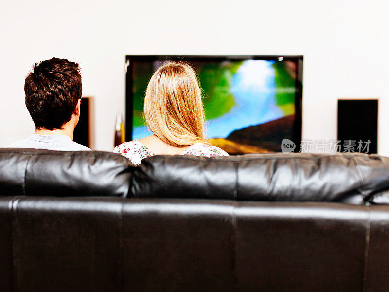 心满意足的年轻夫妇在家看电视的背影