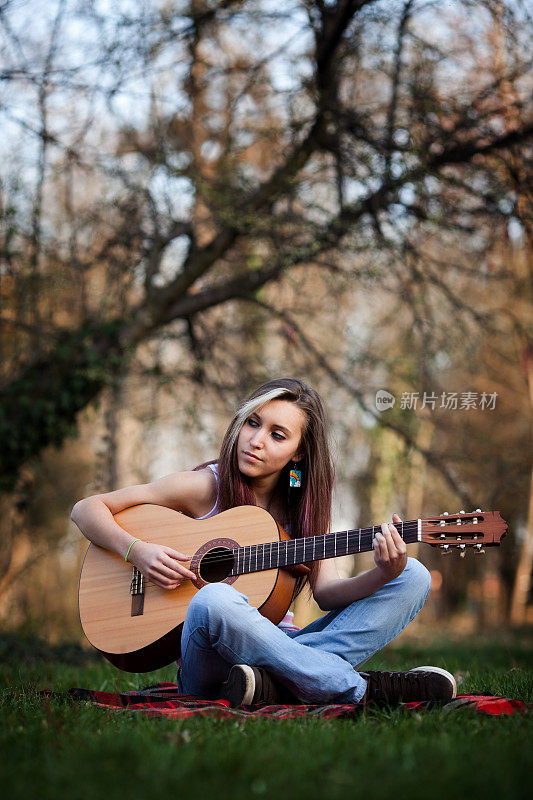 在公园里弹吉他放松的漂亮女孩
