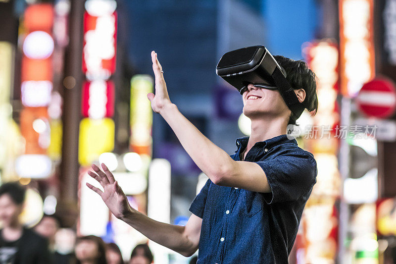 一名日本年轻人在街上使用虚拟现实头盔
