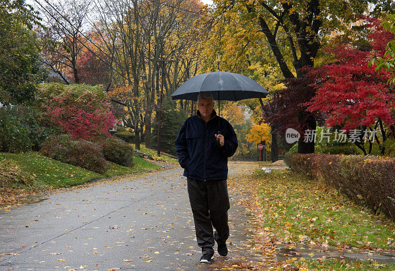 人们在秋雨中走在乡间小路上