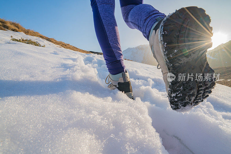 低角度的年轻女子徒步在雪山小径