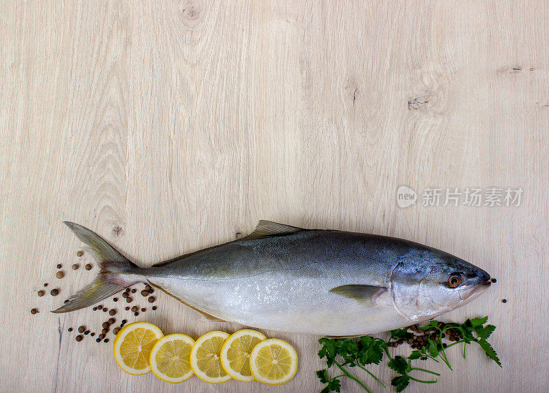 新鲜的鱼与柠檬，欧芹和香料分开放在木板上
