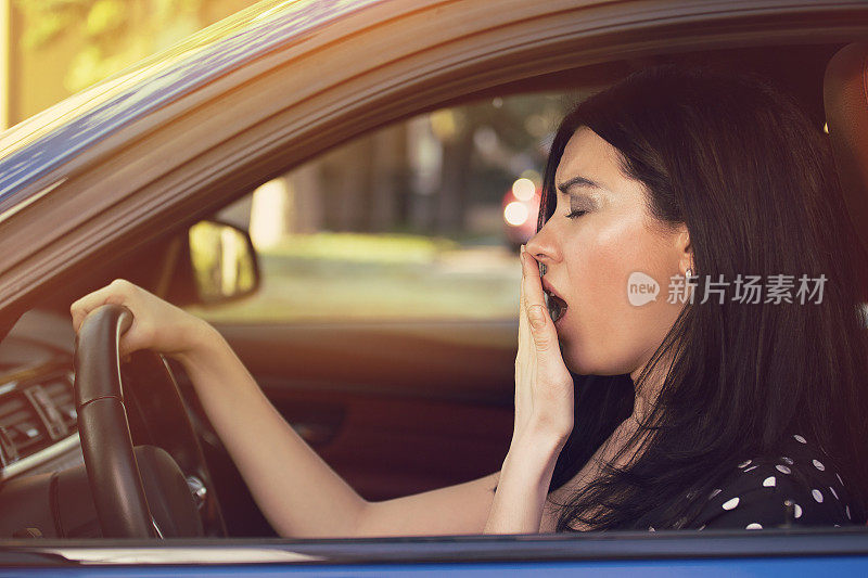 昏昏欲睡打哈欠疲惫的年轻女子驾驶她的车