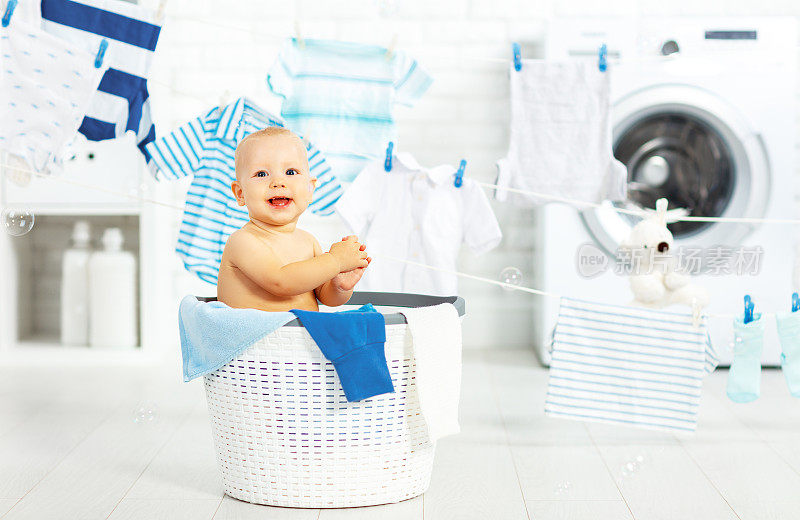 开心的宝贝男孩洗衣服，笑在洗衣房