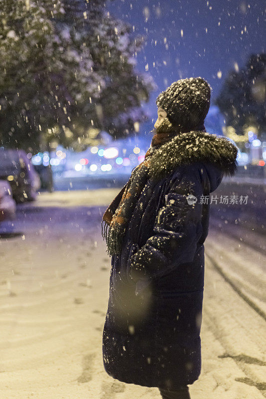 美丽的女人站在雪地里的街道上