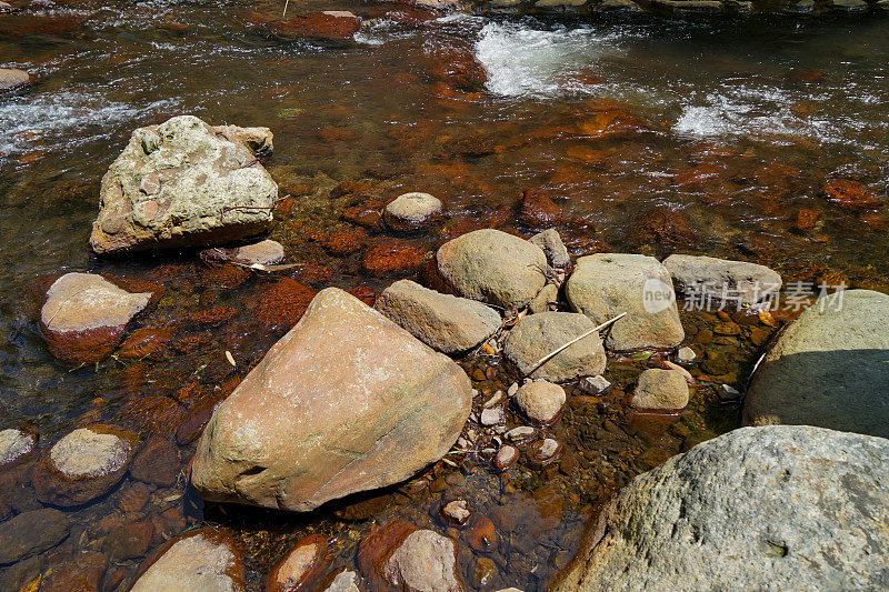 清澈的淡水溪流流经天然河流，坚硬的岩石与青苔，小波浪和光反射背景在黑川温泉镇