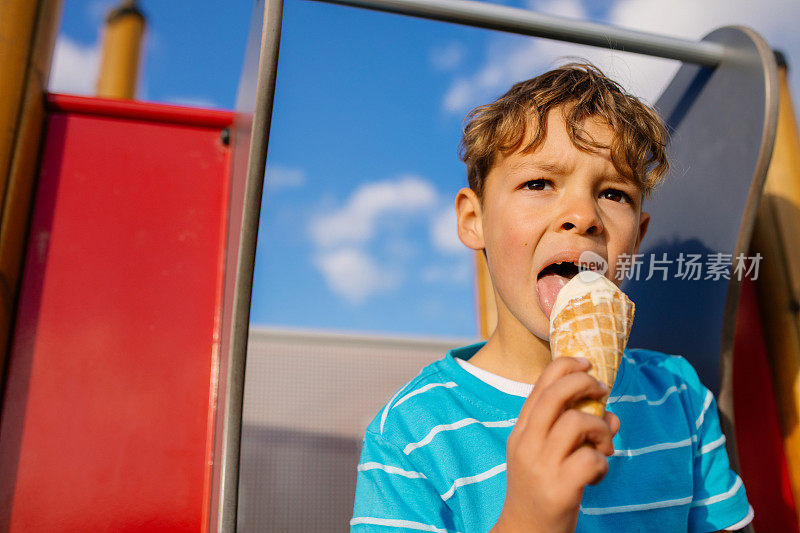 男孩坐在滑梯上吃冰淇淋