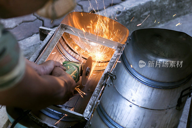 工人们使用金属磨床切割钢制品，产生火花。