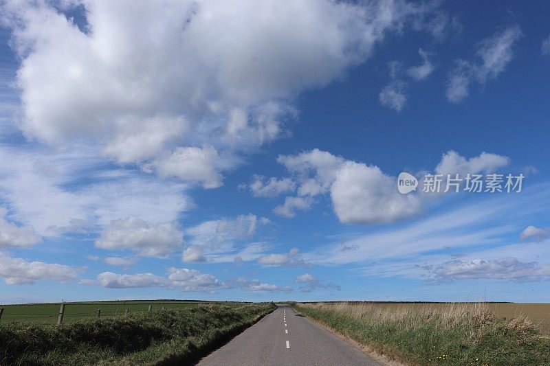蓝天下狭窄的柏油马路和蓬松的白云