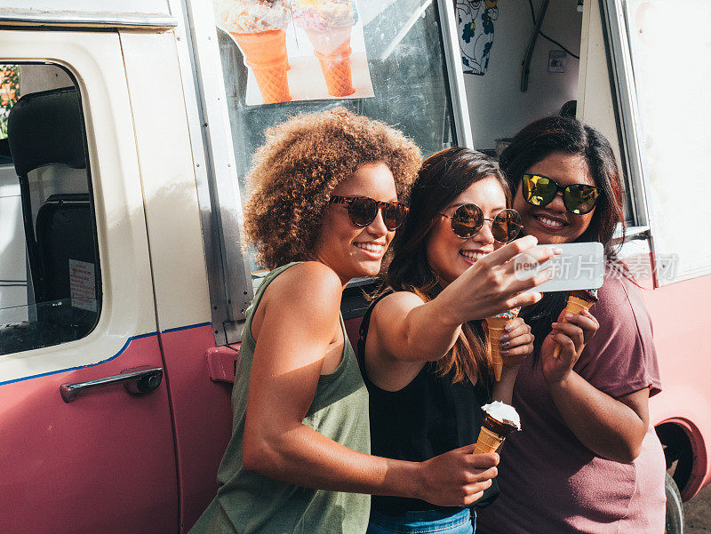 在澳大利亚，三个女孩在冰淇淋车旁边吃冰淇淋
