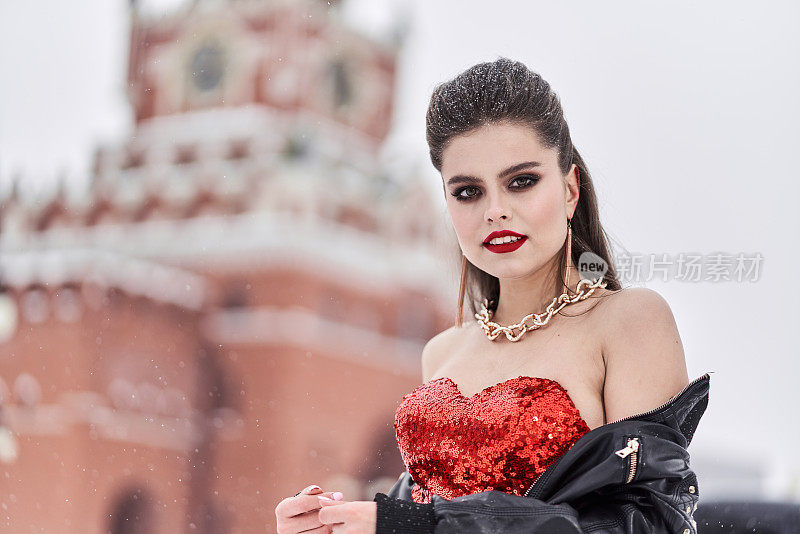 女时装模特的肖像在红色晚礼服和在黑色摩托车夹克户外