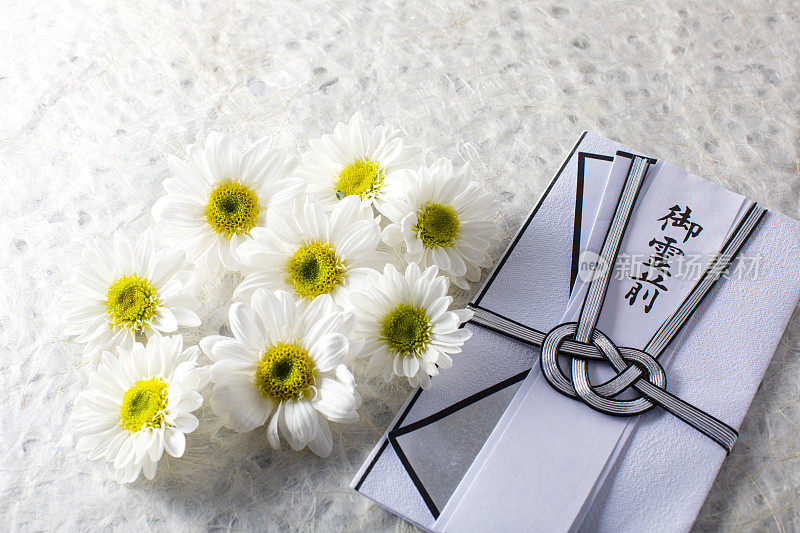 日本葬礼仪式的一项。慰问金和白色的菊花放在日本报纸的顶部。