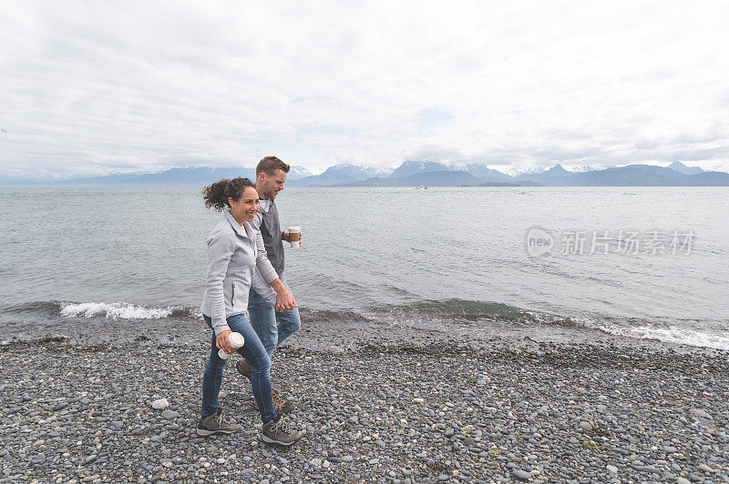 一对年轻的夫妇在一个多岩石的海湾散步