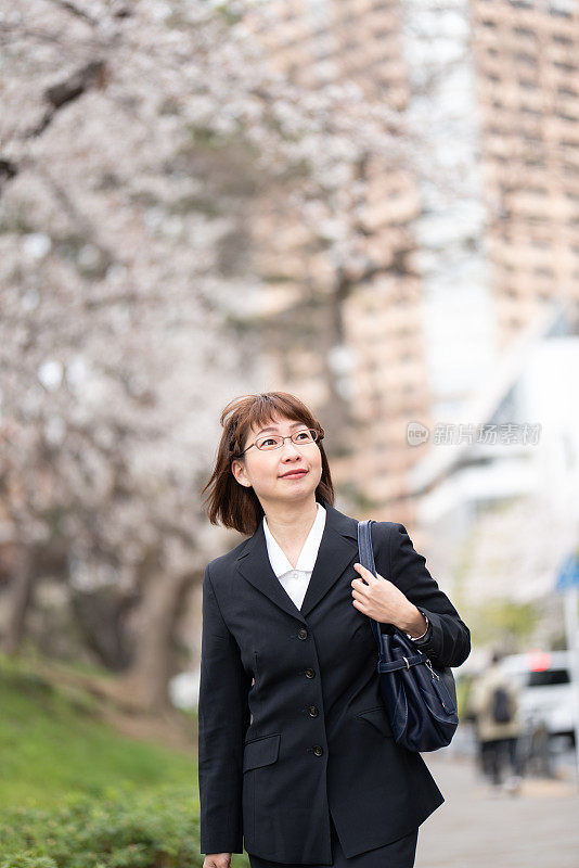 女商人走在樱花盛开的街上