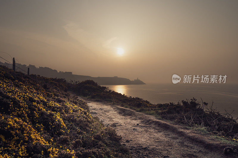 日出在一个夏天沿着悬崖小径散步，崎岖的海岸线和平静的水