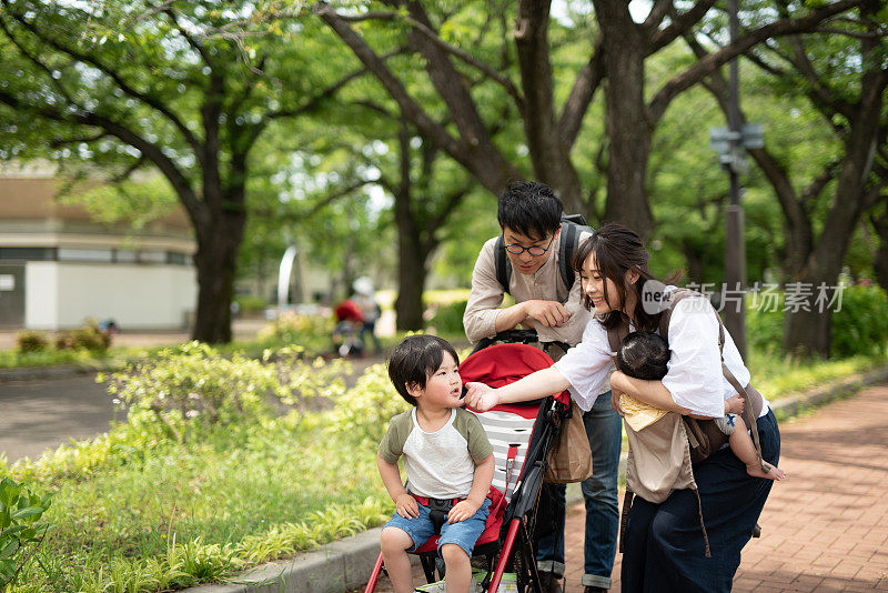 一家人推着婴儿车在公园散步