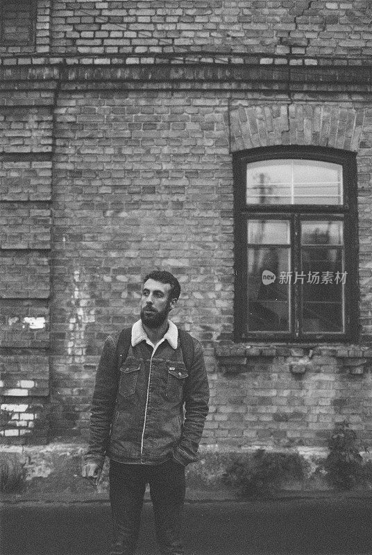 一个男人站在老建筑附近的黑白胶片照片