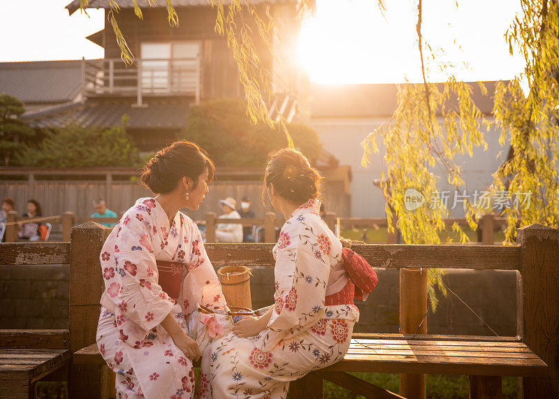 年轻的姐妹们在传统的日本村庄的河边休息