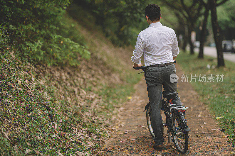 一名亚洲华人白领管理人员与折叠自行车的通勤后视图