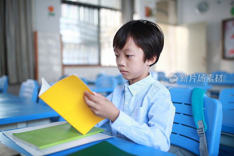 小男孩在教室里的书桌前读书