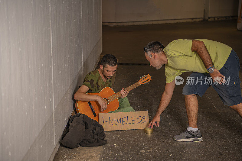 一个人在街上帮助一个乞丐