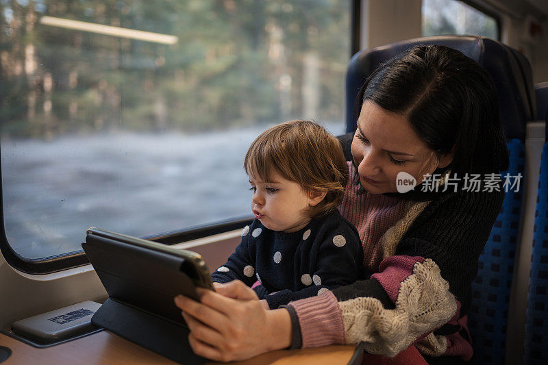 年轻的母亲带着她美丽的孩子乘火车旅行，穿过美丽的风景