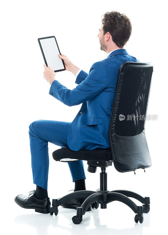 白种年轻男性商人穿着智能休闲装，使用数码平板电脑休息