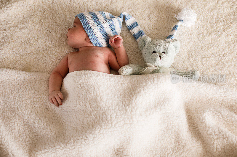 刚出生的婴儿和一只泰迪熊躺在床上