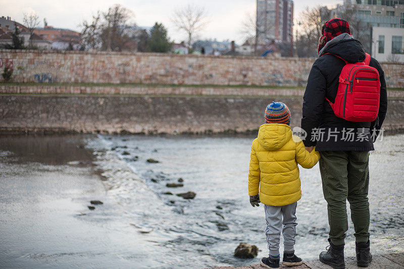 父亲和儿子手牵着手渡河的照片