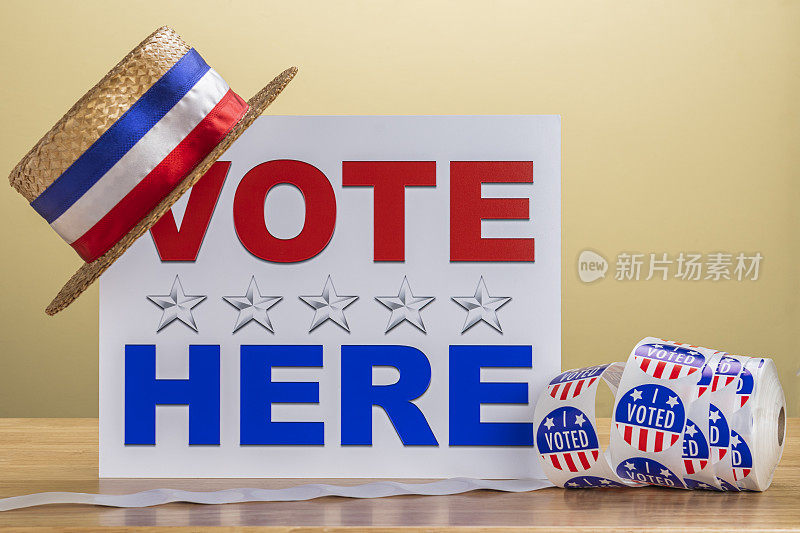 在一个投票站，一顶插在“这里投票人”牌子上的便帽和一卷“我投票了”的贴纸。