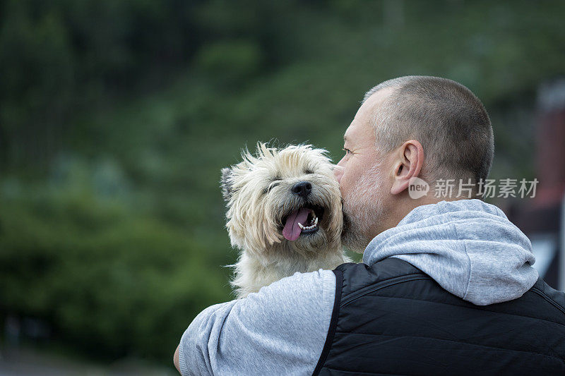 一个成熟的男人在户外亲吻他的狗