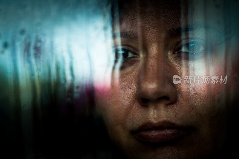 沮丧的女人望着下雨的窗外