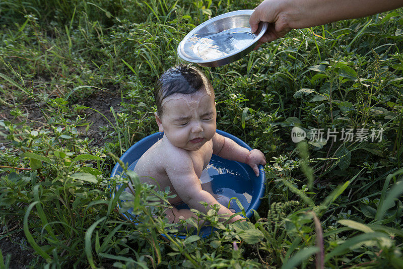 可爱的小男孩在盆子里，在花园里洗澡