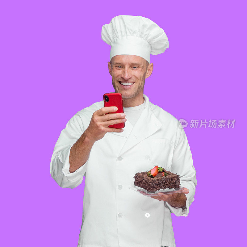 白色男厨师前面在紫色的背景穿着夹克，拿着蛋糕和使用短信