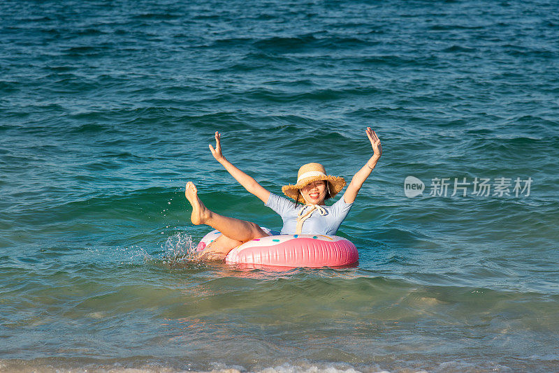 女人游泳和漂浮在海边的水与甜甜圈浮