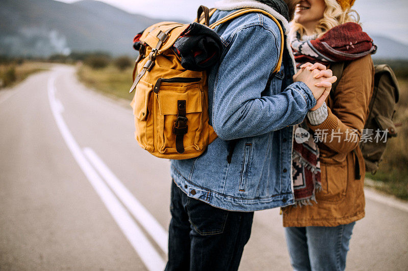 年轻的冒险家夫妇在乡村路上徒步旅行