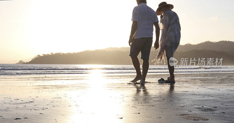 日出时分，一对成熟的夫妇在沙滩上散步