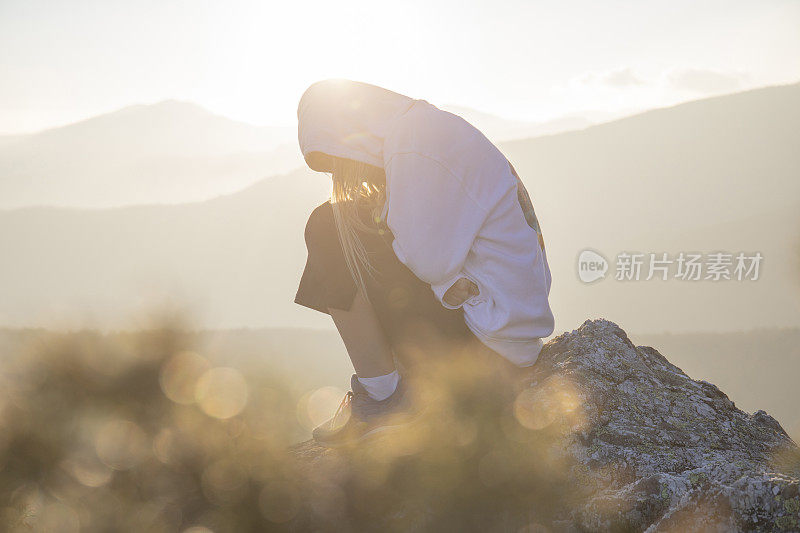 清晨，女徒步旅行者在阳光明媚的山脊上放松