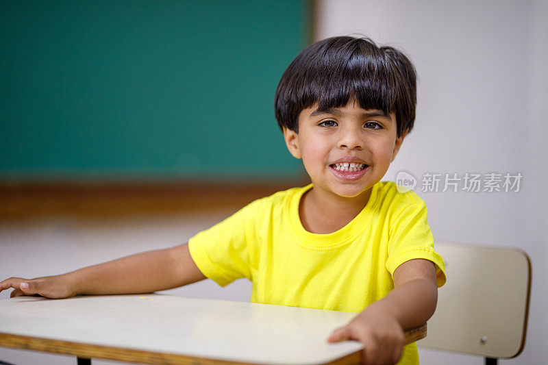 小男孩在教室里微笑着看着摄像机