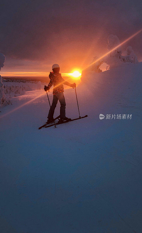 一个年轻女子在明亮的日落背景上滑雪。白雪覆盖的滑雪场。多雪，冬天的风景和很多雪。