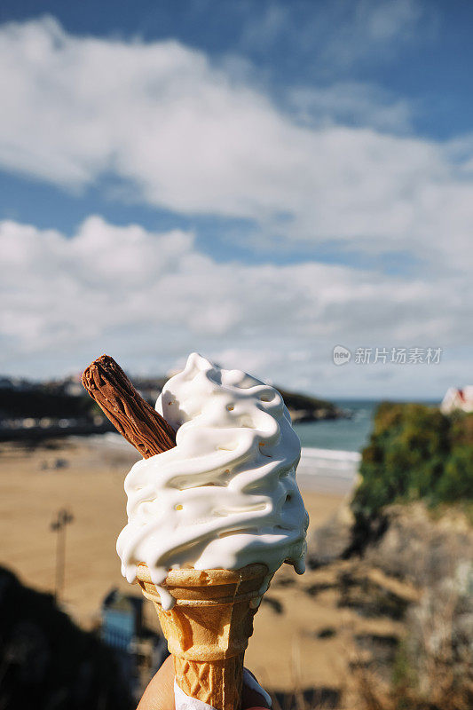 在一个晴朗的秋日，康沃尔纽基的托万海滩上，一只手拿着一个融化的冰淇淋。