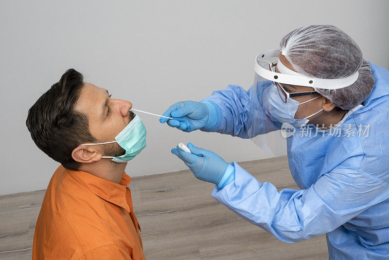 女医生正穿著防护服，从男病人的鼻子上取喉拭子作化验