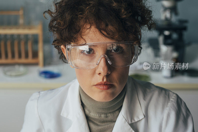 一个科学家的肖像:一个女人在实验室里穿着实验服戴着护目镜工作