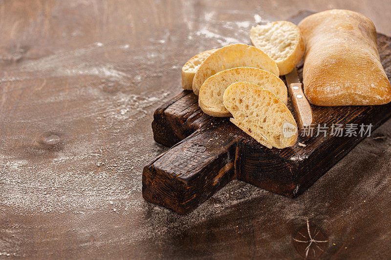 切成“u200b”u200意大利脆皮意大利面包，置于切菜板上，棕色背景