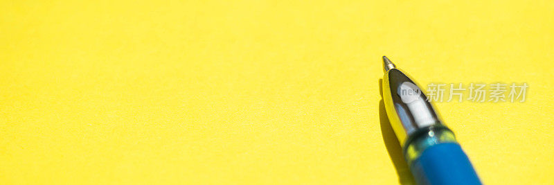 蓝色圆珠笔在阳光黄色纸上的特写