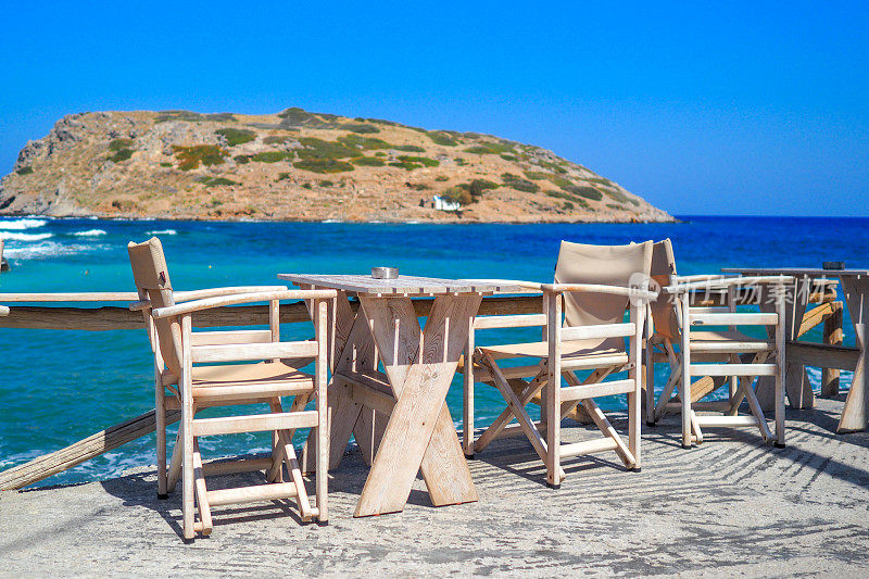 空的乡村木桌和椅子的露台在海滨