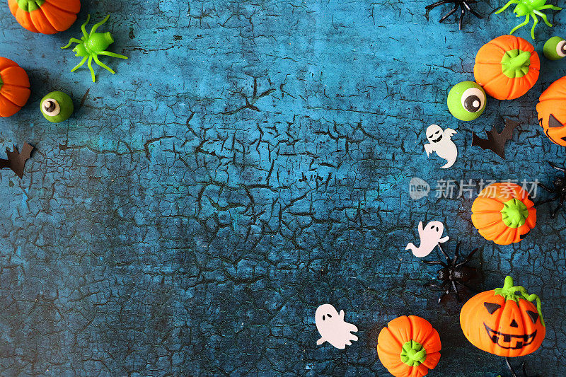 万圣节设计海报形象，自制剪影裁剪形状的蝙蝠，幽灵，蜘蛛，橙色糖霜南瓜杰克灯和绿色的眼球，在蓝色裂纹背景，万圣节墙纸背景，复制空间