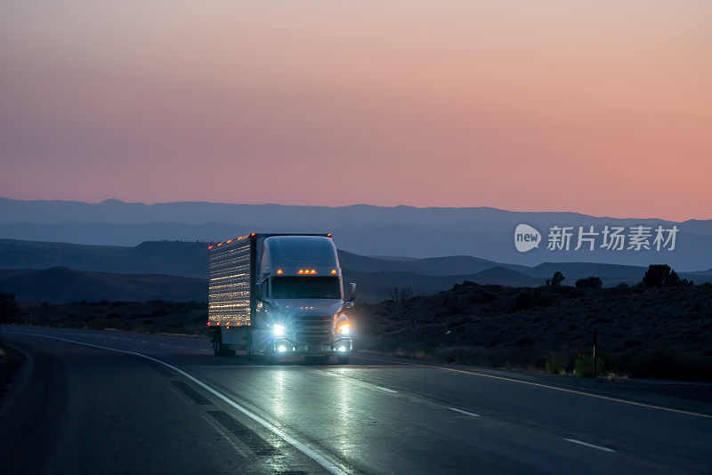 在沙漠公路上，一辆往东的商业货运半挂车，一个戏剧性的日落背景